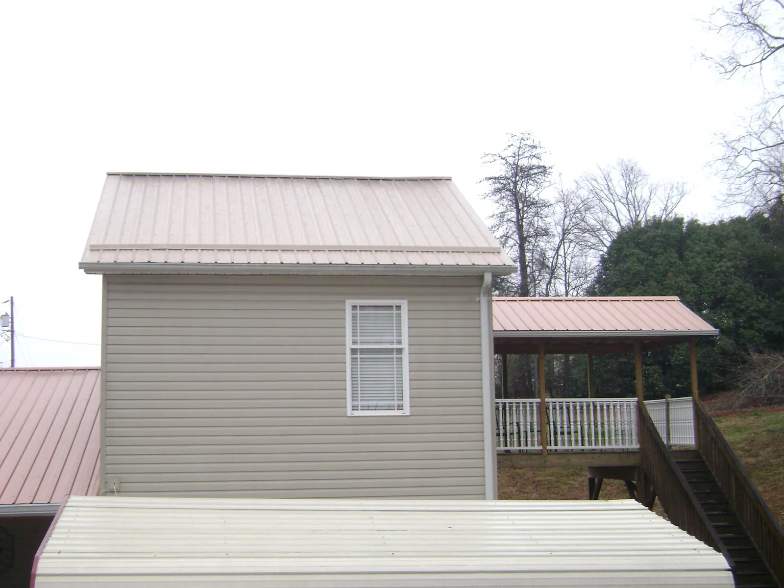 Tan metal roofs on a two story addition and attached porch, from a Roof Replacement job in Center Valley