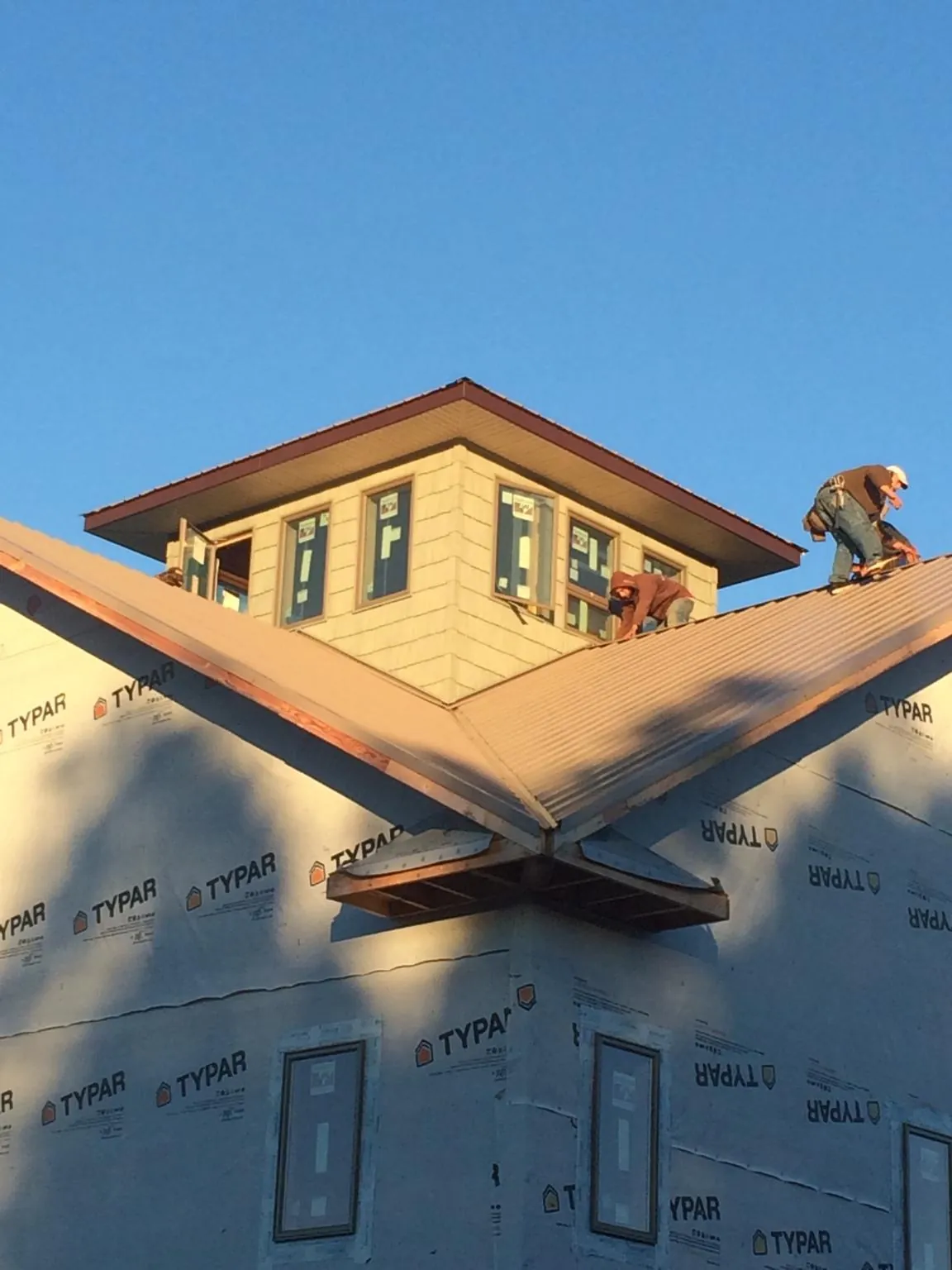 Roofers working around a rooftop cupola on a new metal roof at sunset — Roof Waterproofing in Center Valley by Roofing Brothers